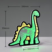 Grün-gelbe LED-Dekoleuchte in Dinosaurierform (Langhals) mit schwarzem Rand auf weißem Sockel, Maße ca. 330 mm breit und 334 mm hoch, Ansicht schräg von vorn vor grauem Hintergrund