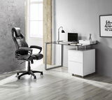 Moderner Schreibtisch mit Glasplatte und weißem Unterschrank, seitliche Perspektive, neben einem schwarzen Bürostuhl in einem stilvollen Raum.