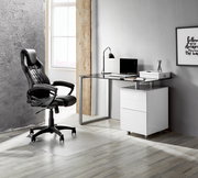 Moderner Schreibtisch mit Glasplatte und weißem Unterschrank, seitliche Perspektive, neben einem schwarzen Bürostuhl in einem stilvollen Raum.