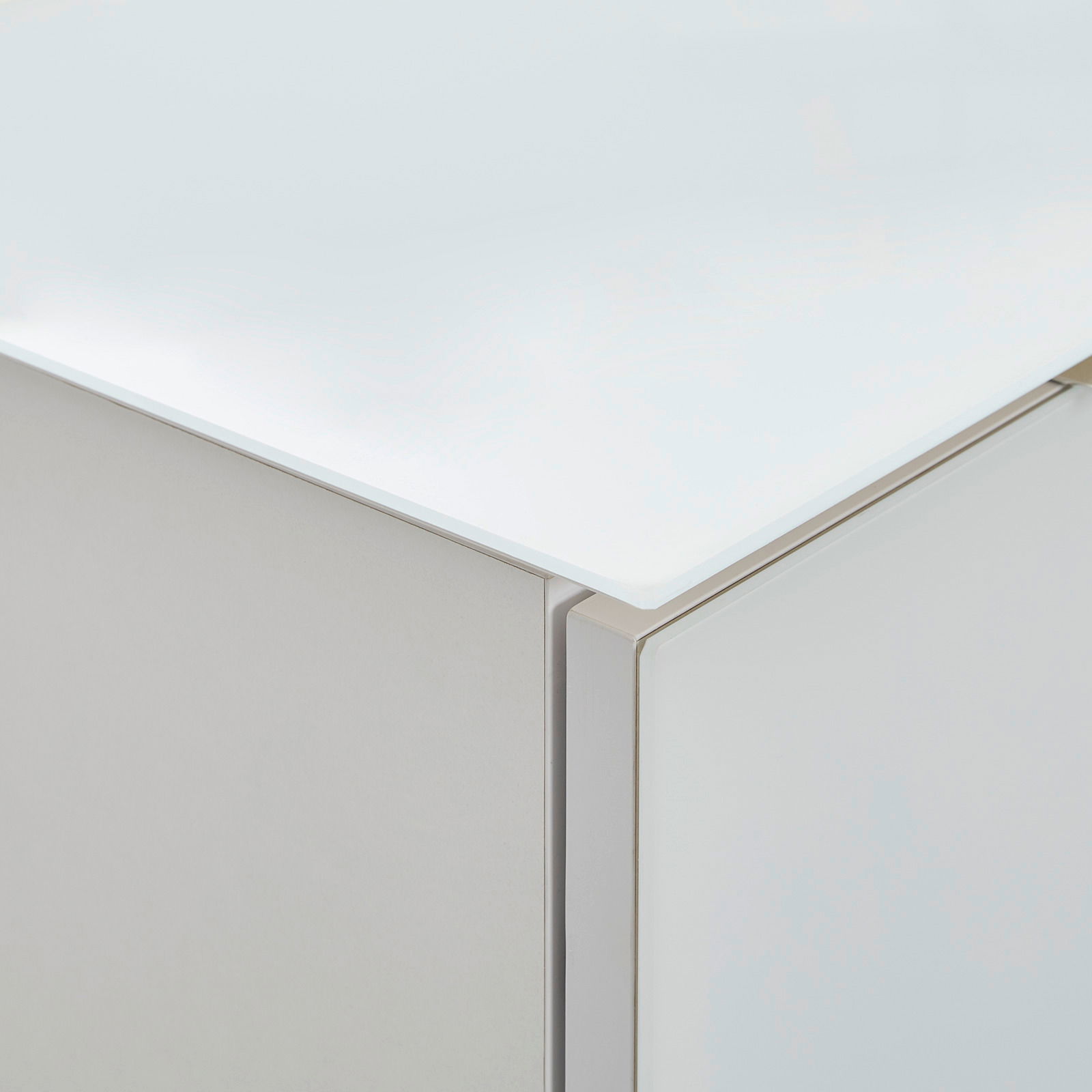 Nahaufnahme einer Ecke eines Highboards mit weißer, glänzender Oberfläche und klaren Linien.
