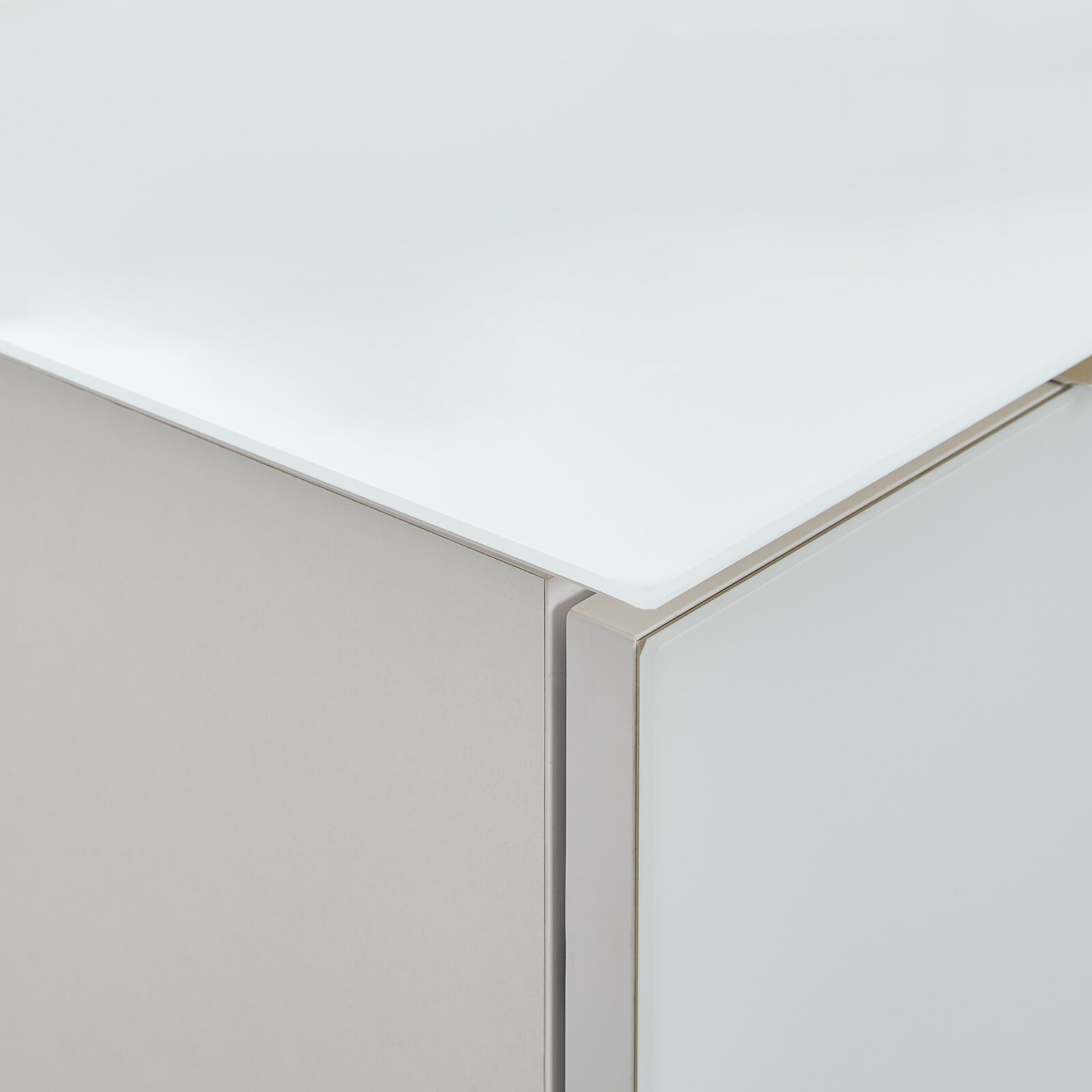 Nahaufnahme einer Ecke eines Highboards mit weißer, glänzender Oberfläche und klaren Linien.