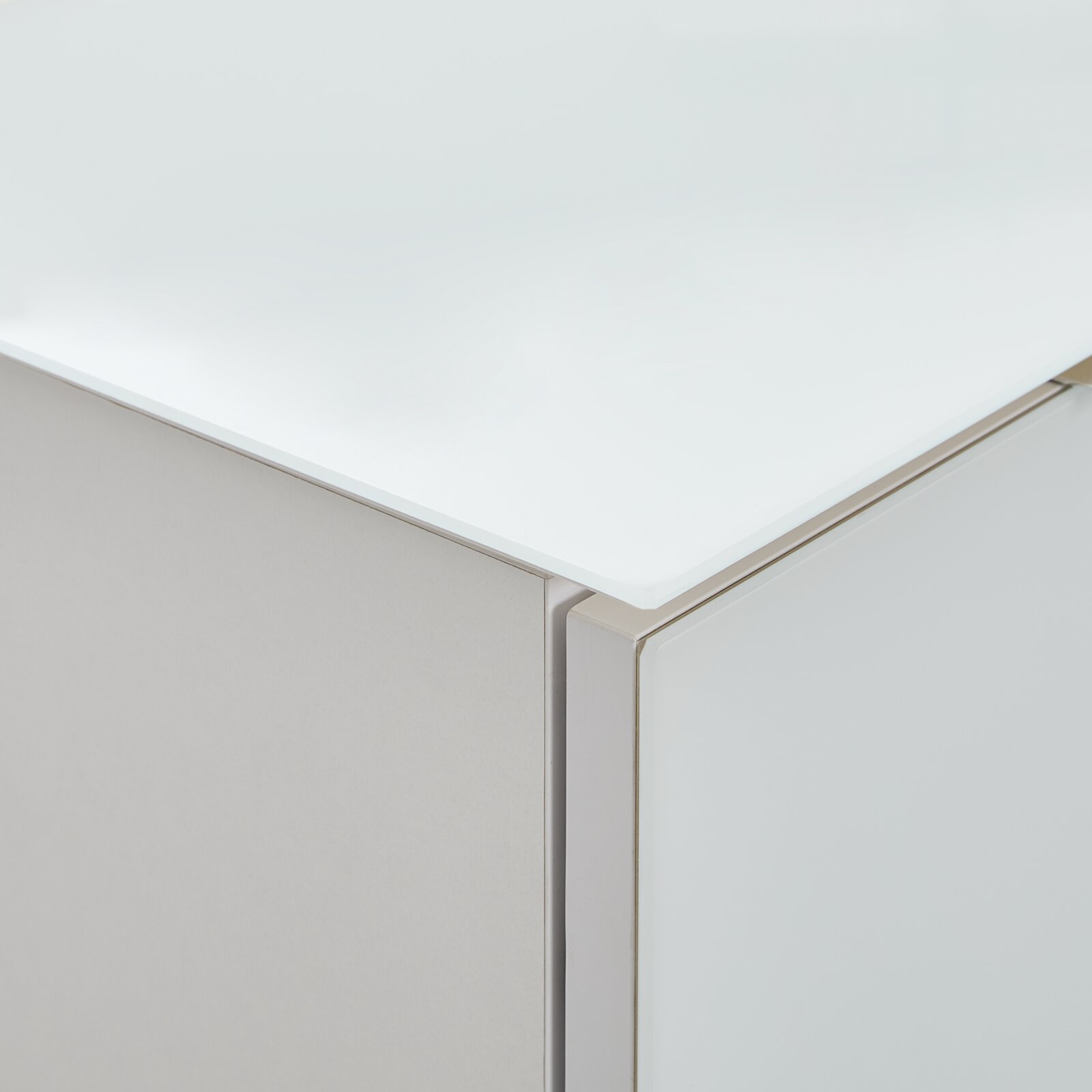 Nahaufnahme einer Ecke eines Highboards mit weißer, glänzender Oberfläche und klaren Linien.