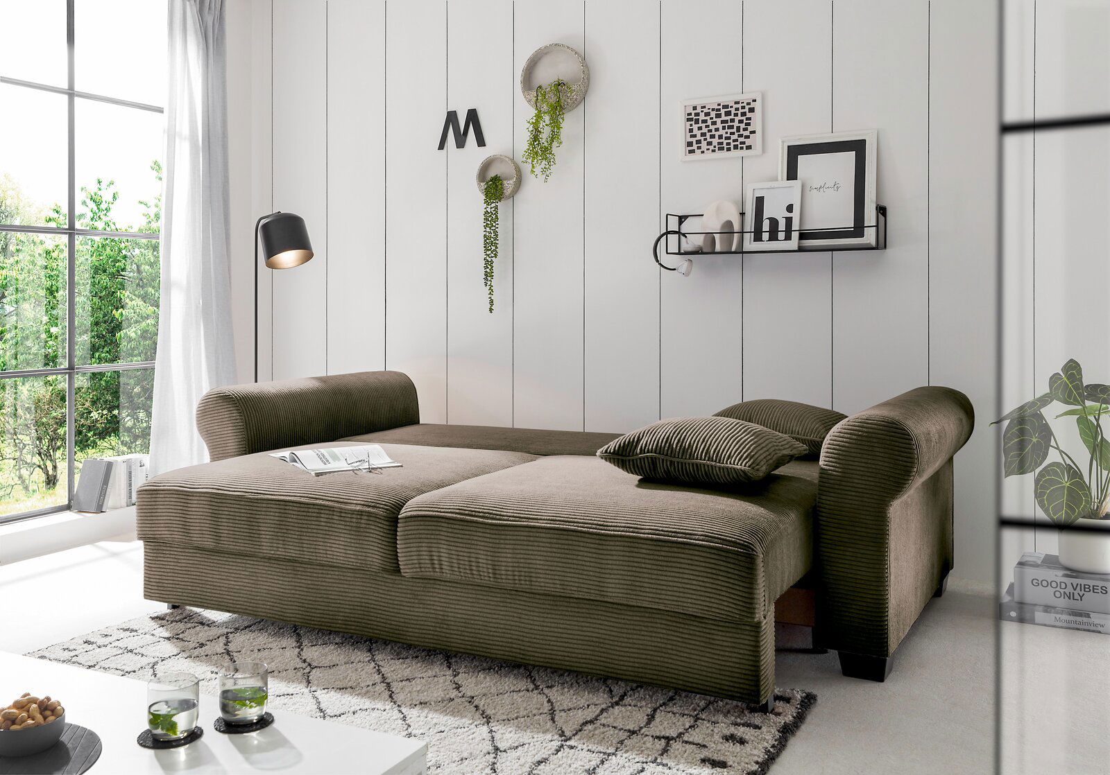 Funktionssofa in einem modernen Wohnzimmer, seitliche Perspektive, mit grüner Polsterung und dekorativen Kissen.