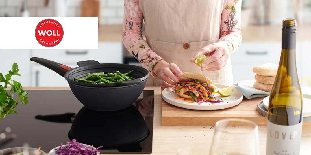 Eine Person bereitet in einer modernen Küche ein Sandwich zu, während grüne Bohnen in der Pfanne kochen.