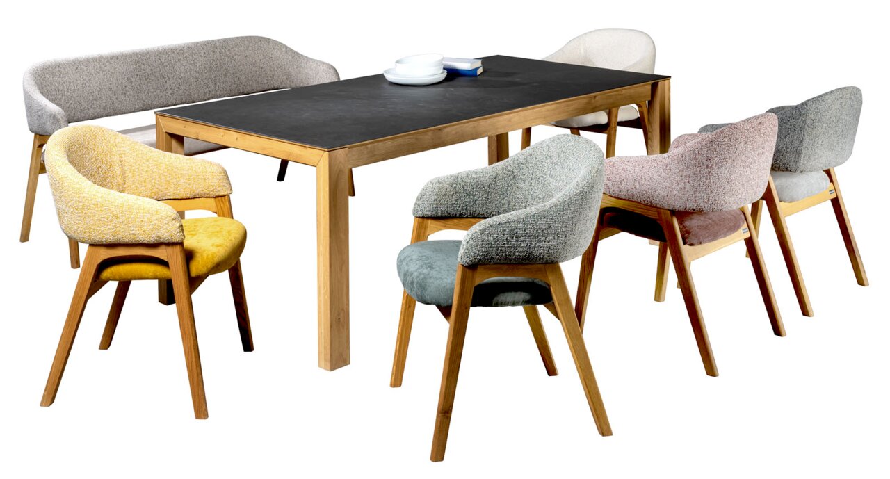 Modernes Esszimmer-Set mit rechteckigem Holztisch und dunkler Tischplatte, umgeben von gepolsterten Stühlen in verschiedenen Farben, freigestellt auf Weiß, Perspektive: schräg von vorne in leichter Seitenansicht