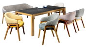 Modernes Esszimmer-Set mit rechteckigem Holztisch und dunkler Tischplatte, umgeben von gepolsterten Stühlen in verschiedenen Farben, freigestellt auf Weiß, Perspektive: schräg von vorne in leichter Seitenansicht