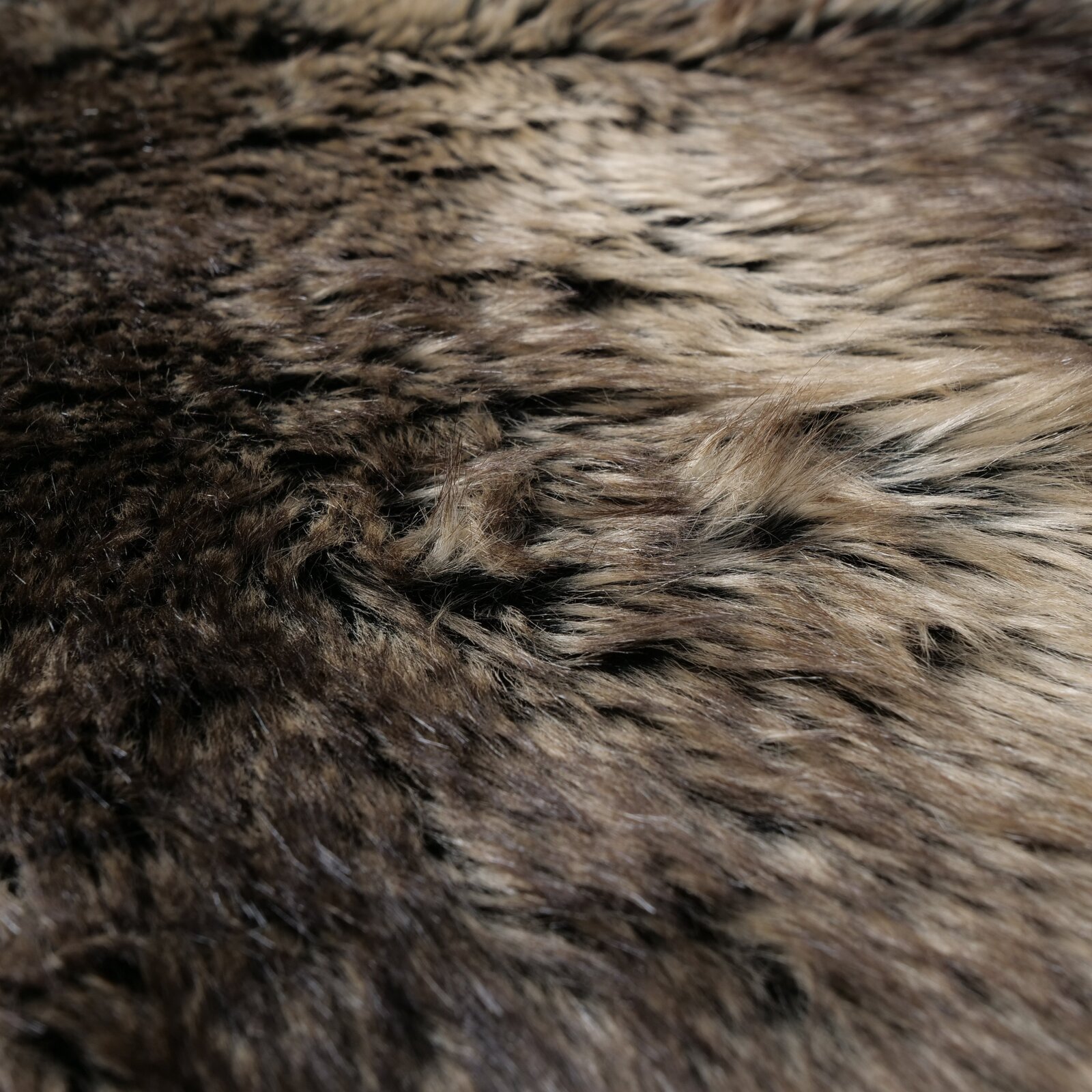 Close-up van een decoratieve vacht in natuurlijke bruintinten met een zachte, donzige textuur.