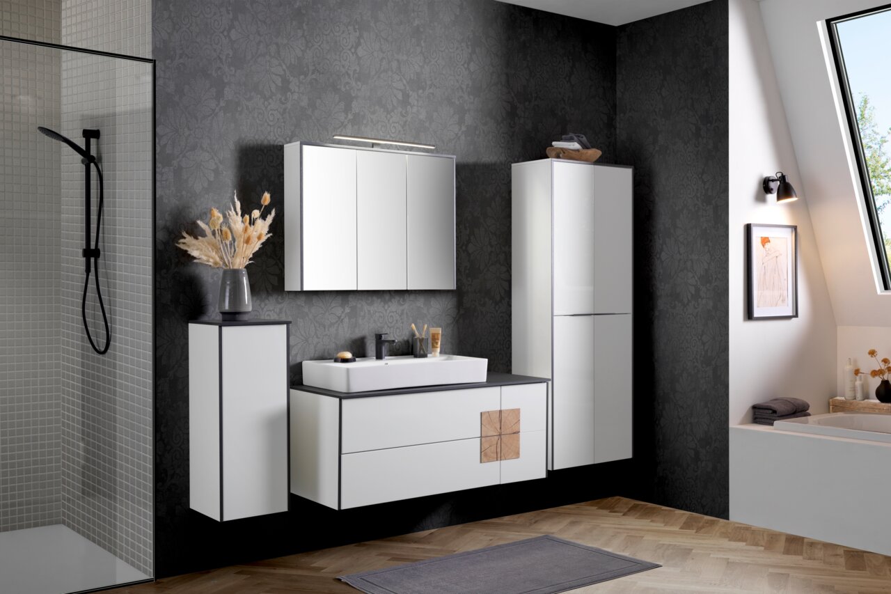Modernes Waschtisch-Set in einem stilvollen Badezimmer mit dunkler Tapete, bestehend aus einem Waschbecken mit Unterschrank, einem Spiegel und einem hohen Schrank, seitliche Perspektive.