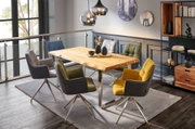 Esszimmer mit modernem Holztisch und Metallgestell, umgeben von bunten Drehstühlen, aus der Perspektive eines offenen Wohnbereichs fotografiert.