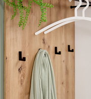 Nahaufnahme einer Kompaktgarderobe aus Holz mit schwarzen Haken, einem grünen Tuch und weißen Kleiderbügeln, von vorne betrachtet.