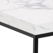 Nahaufnahme eines Couchtischs mit weißer Marmoroptik und schwarzem Metallrahmen, perspektivisch von der Ecke aufgenommen.
