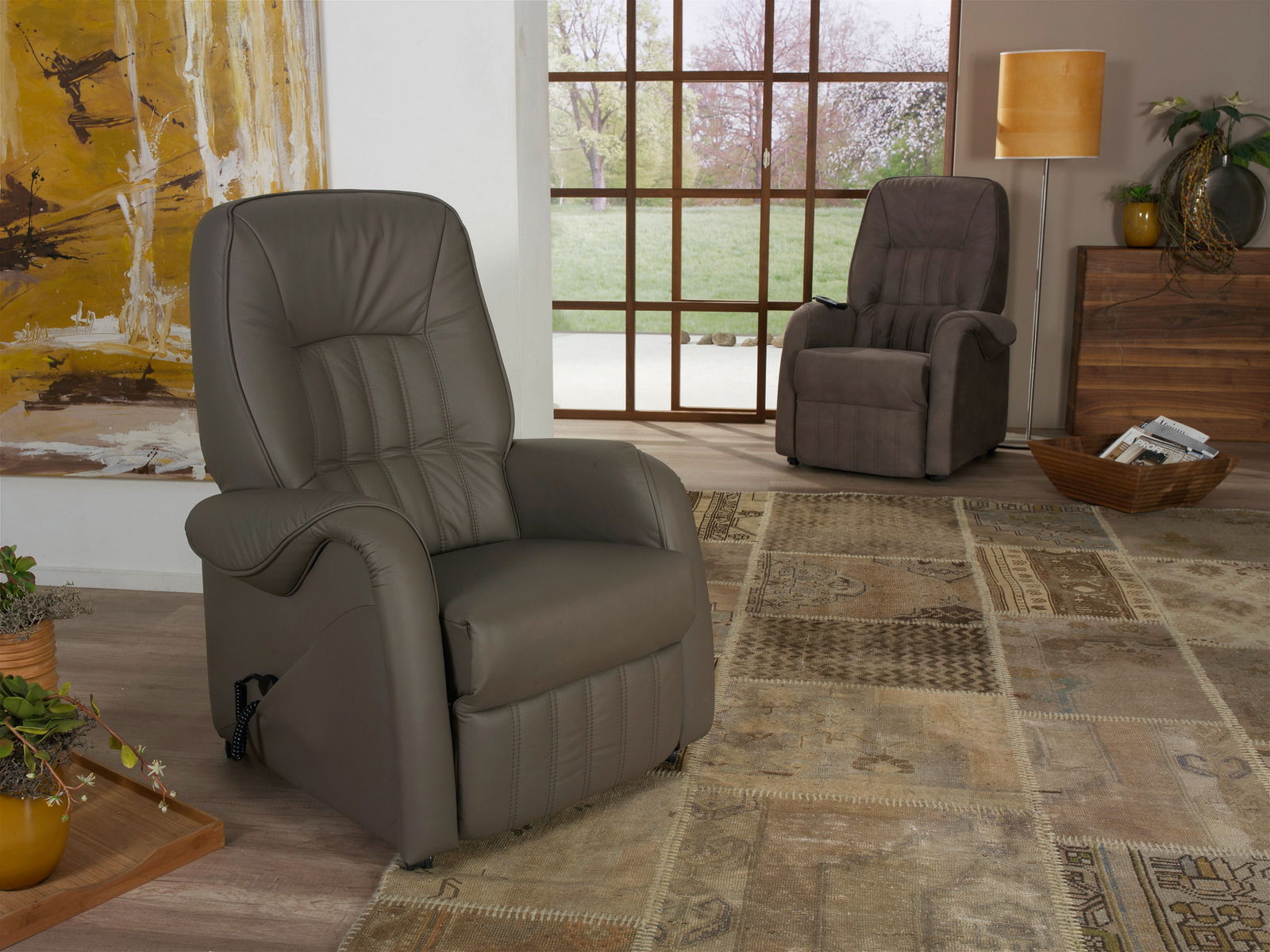 Zwei bequeme Fernsehsessel in einem stilvoll eingerichteten Wohnzimmer, mit Blick auf den vorderen Sessel aus Leder in der linken Bildhälfte.