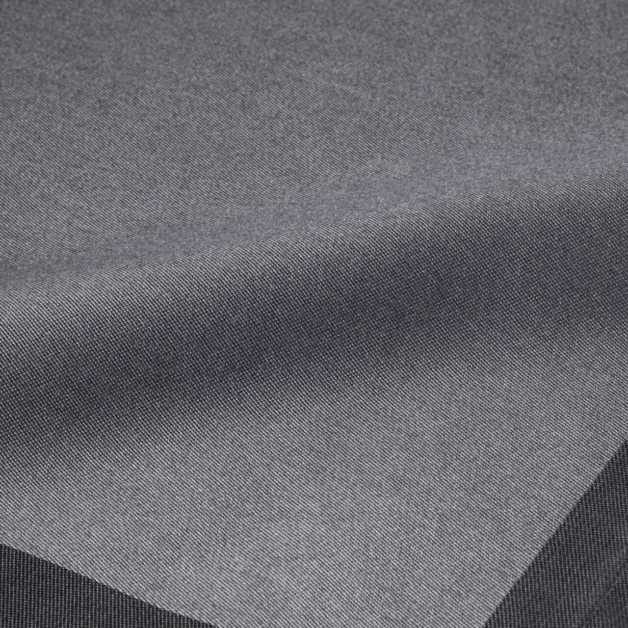 Nahaufnahme einer graphitfarbenen Serviette mit feiner Textur, perspektivisch von oben fotografiert.