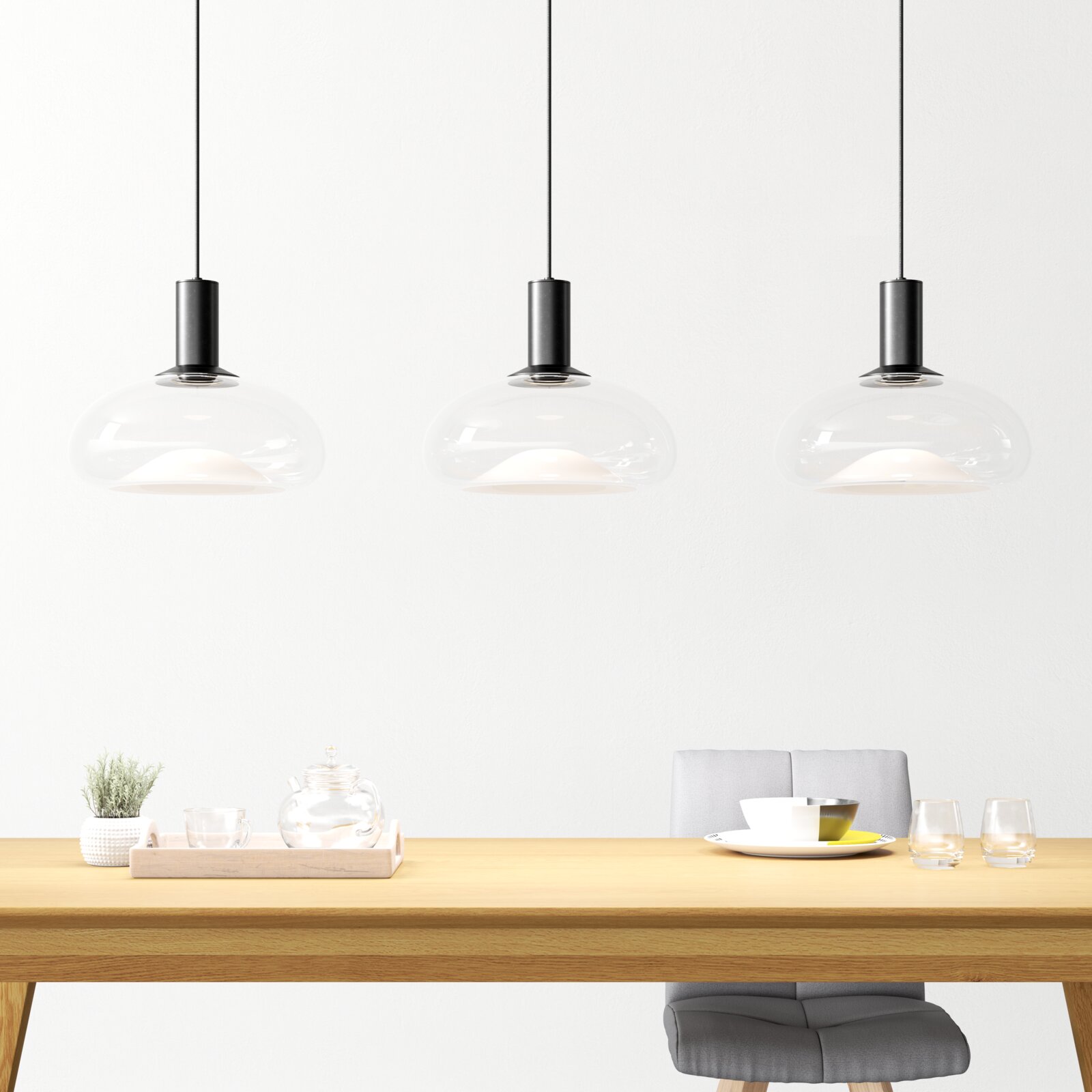 Drei moderne Hängeleuchten aus Glas über einem Esstisch, seitliche Perspektive