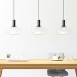 Drei moderne Hängeleuchten aus Glas über einem Esstisch, seitliche Perspektive