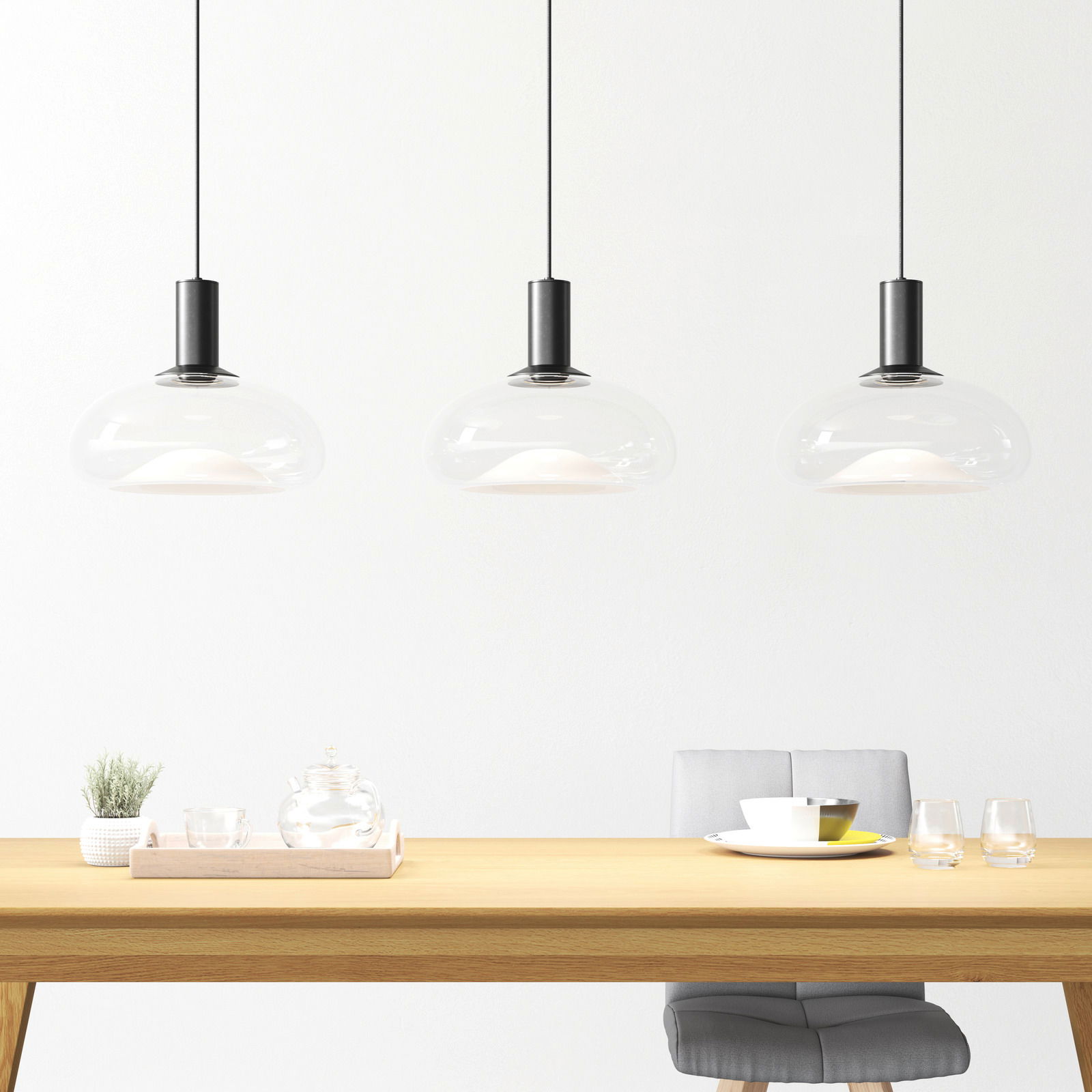 Drei moderne Hängeleuchten aus Glas über einem Esstisch, seitliche Perspektive