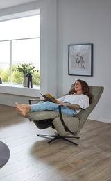 Frau entspannt in einem modernen Relaxsessel mit Blick aus einem großen Fenster.