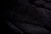 Nahaufnahme einer dunkelgrauen, strukturierten Stoffoberfläche eines Sofas mit Kissen, seitliche Perspektive.