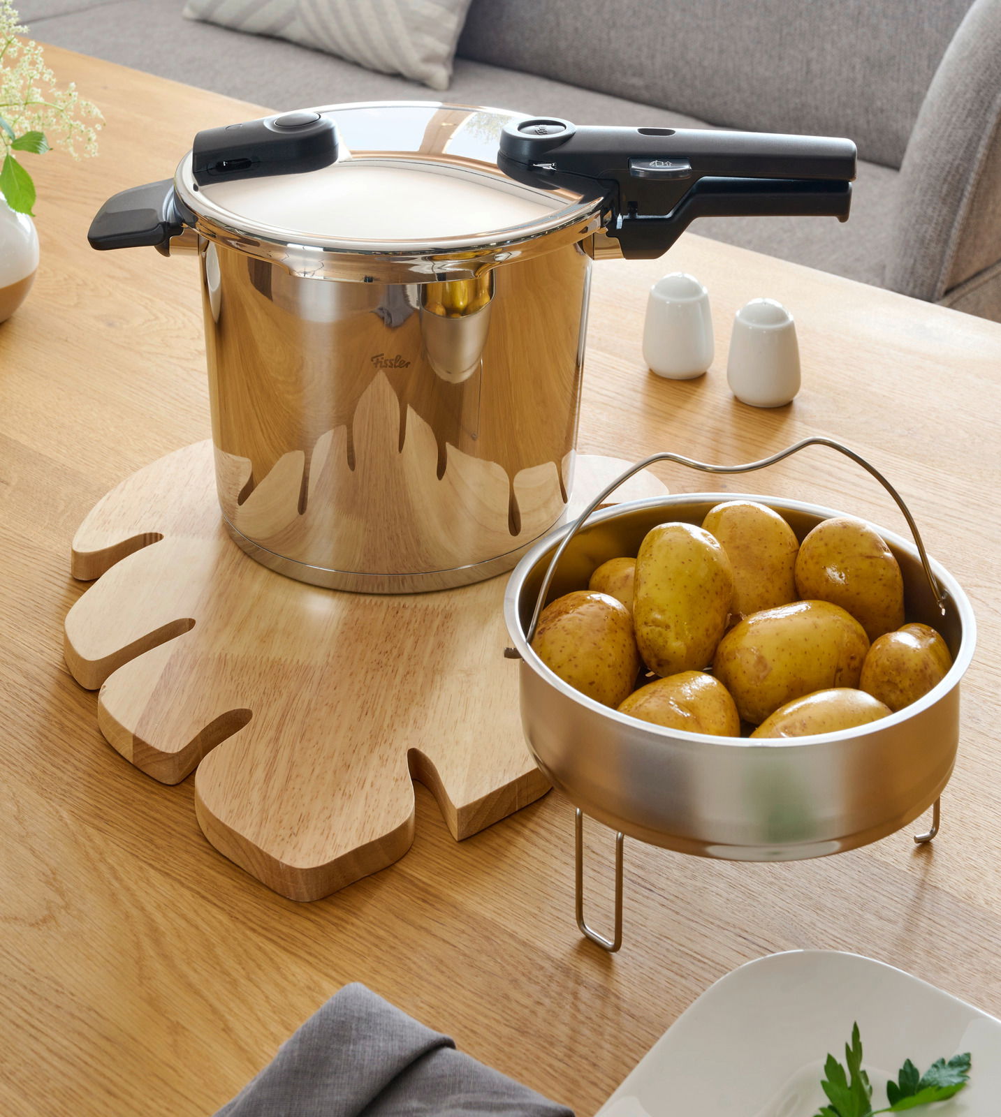 Schnellkochtopf Vitaquick 6 l aus Edelstahl auf einem Holztisch, mit einem Einsatz voller Kartoffeln. Perspektive von oben.