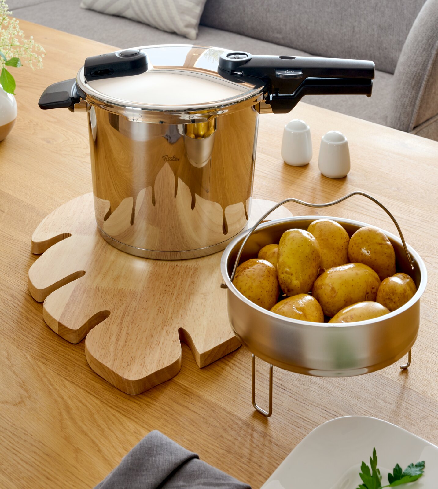 Schnellkochtopf Vitaquick 6 l aus Edelstahl auf einem Holztisch, mit einem Einsatz voller Kartoffeln. Perspektive von oben.