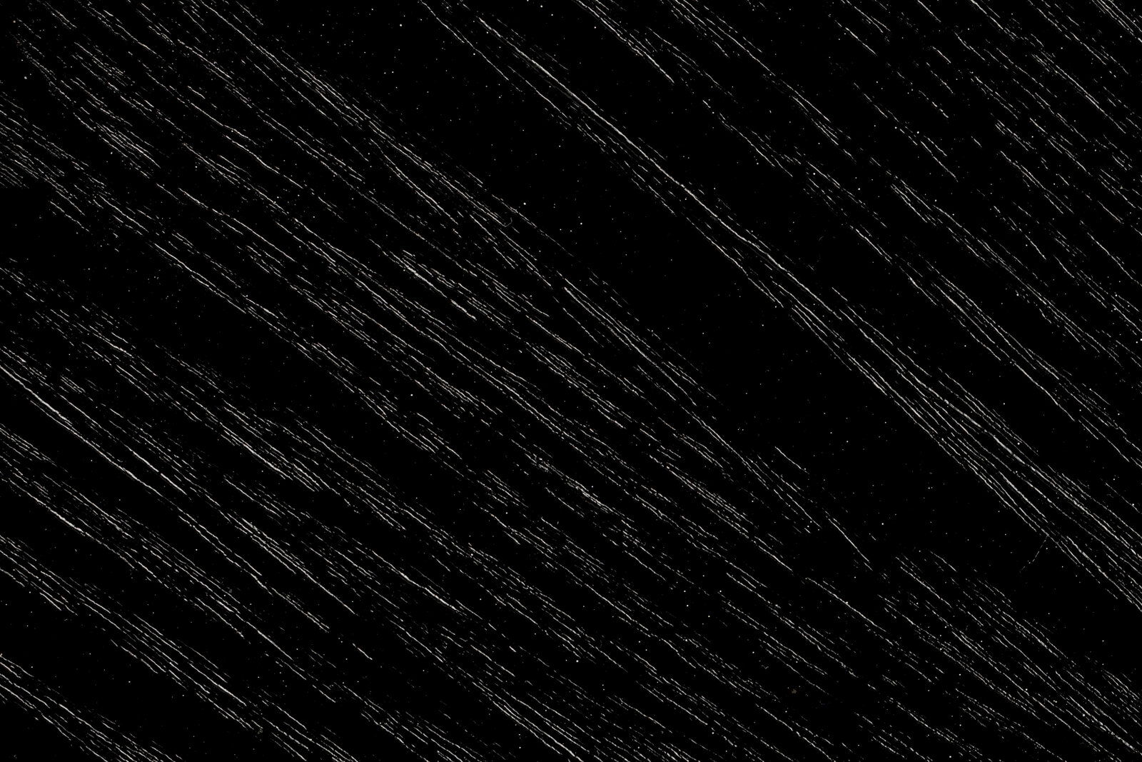 Nahaufnahme der schwarzen Holzmaserung eines Beistelltisches, diagonale Perspektive