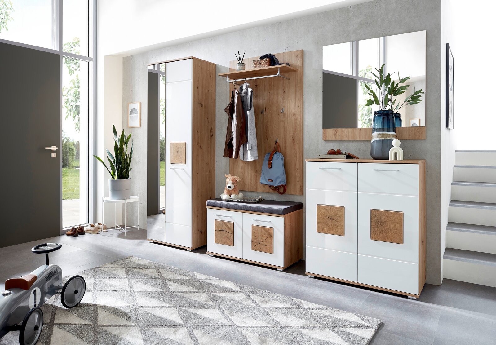 Moderne Garderobeneinrichtung mit Schuhschrank, Spiegel, Garderobenbank und Garderobenpaneel in einem hellen Raum, seitliche Perspektive.