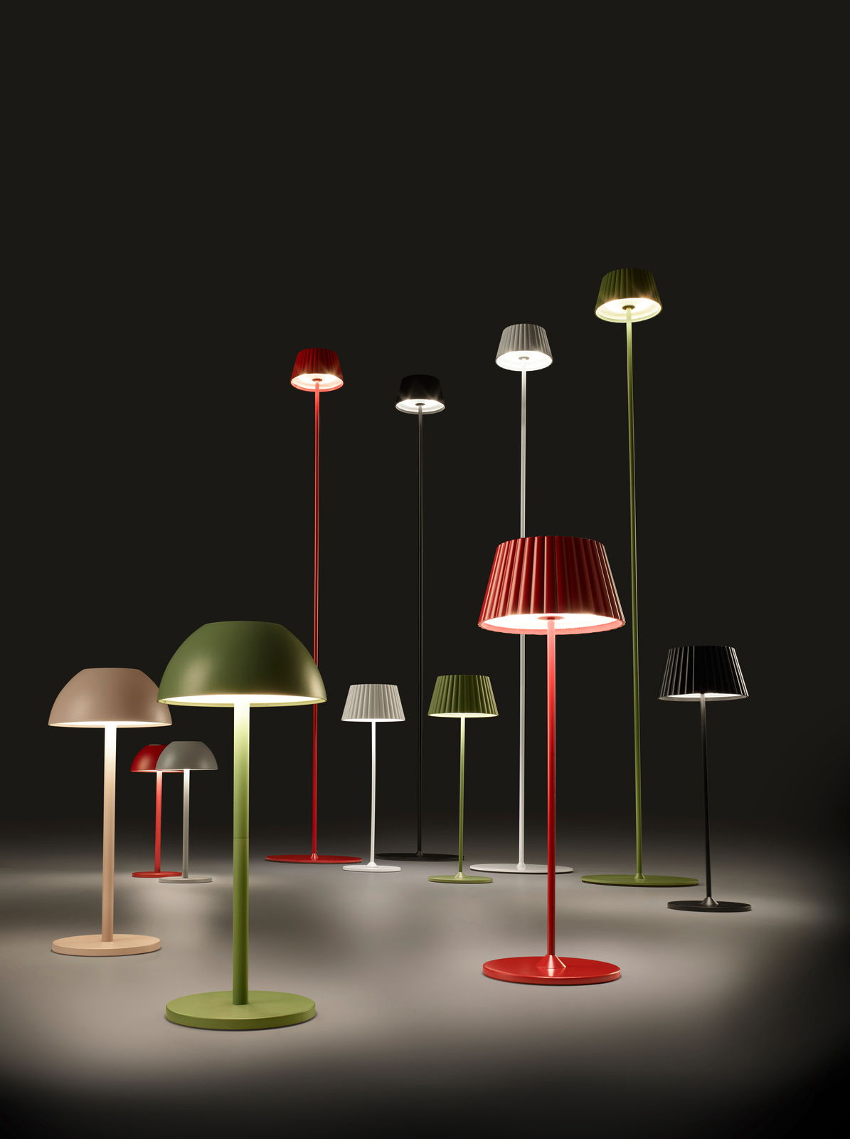 Verschiedene bunte Akku-Stehleuchten SUAREZ in einem dunklen Raum, aus der Perspektive von vorne betrachtet.