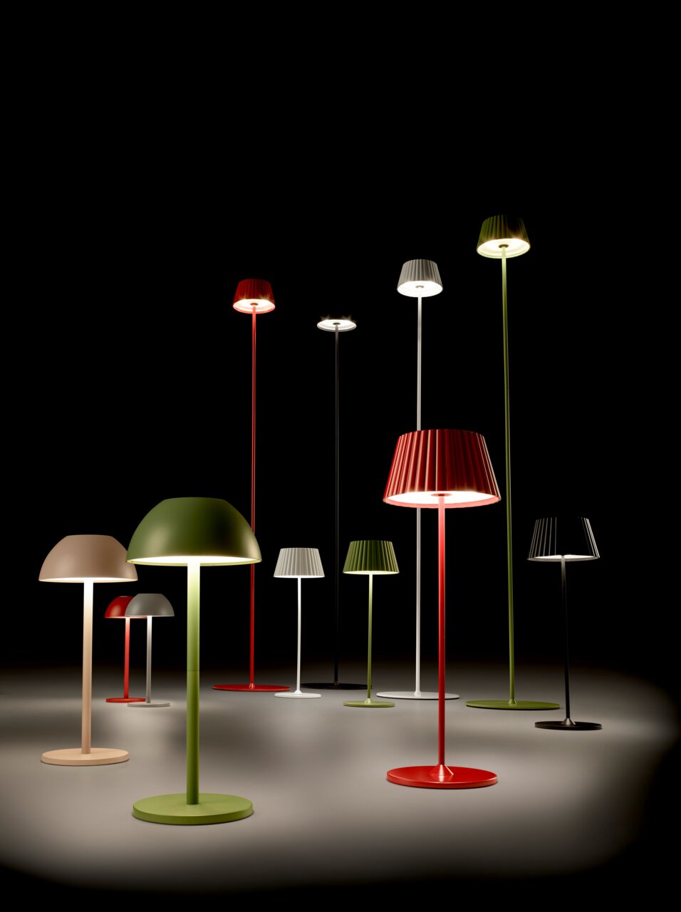Verschiedene bunte Akku-Stehleuchten SUAREZ in einem dunklen Raum, aus der Perspektive von vorne betrachtet.
