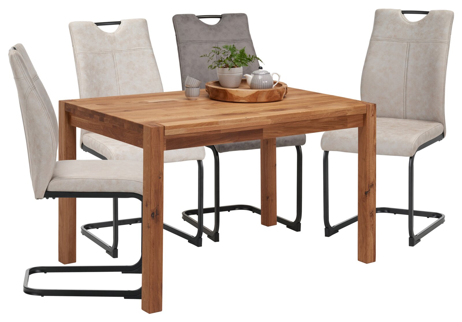 Essgruppe mit rechteckigem Massivholz-Esstisch in Eicheoptik und vier gepolsterten Schwingstühlen in Beige/Grau mit schwarzem Metallgestell, dekoriert mit Tablett, Teekanne und Pflanze, gezeigt in leichter Front- und Seitenansicht (3/4-Perspektive) vor we