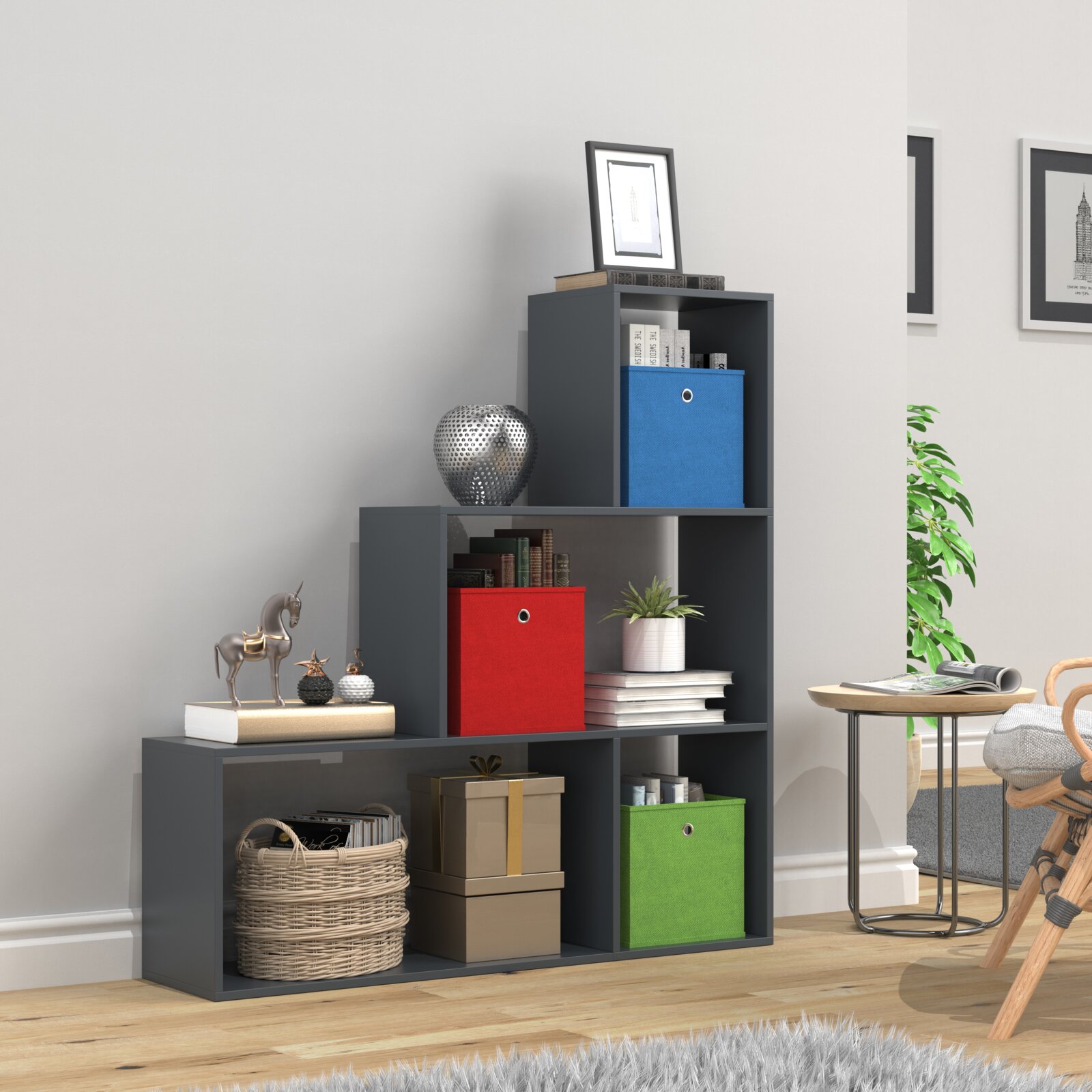 Modernes, stufenförmiges Regal in Anthrazit mit offenen Fächern und farbigen Stoffboxen (blau, rot, grün), dekoriert mit Büchern und Deko im Wohnzimmer, Ansicht schräg von vorne.