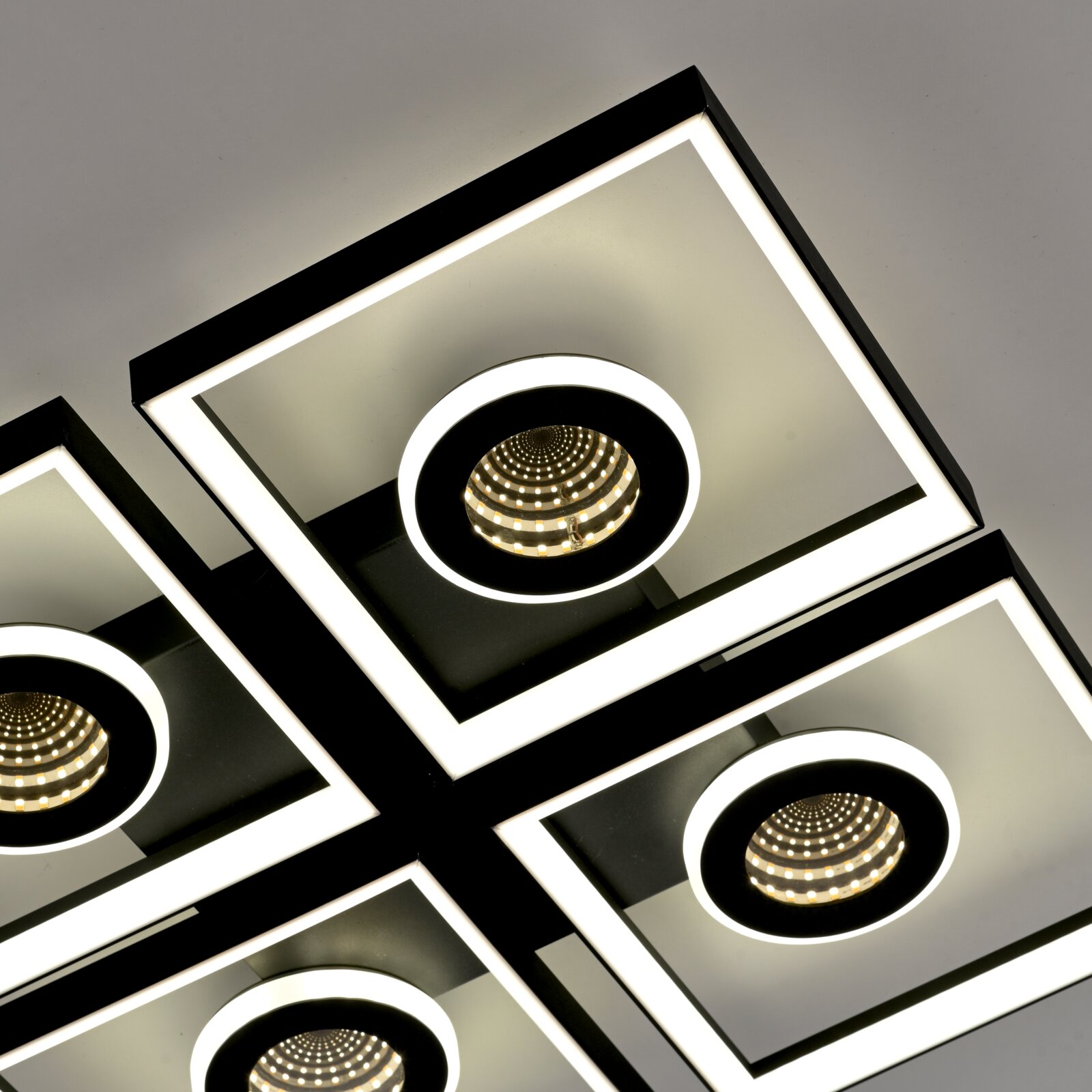 Moderne led-plafondlamp met een vierkant ontwerp en ronde lichtelementen, gezien van onderaf.