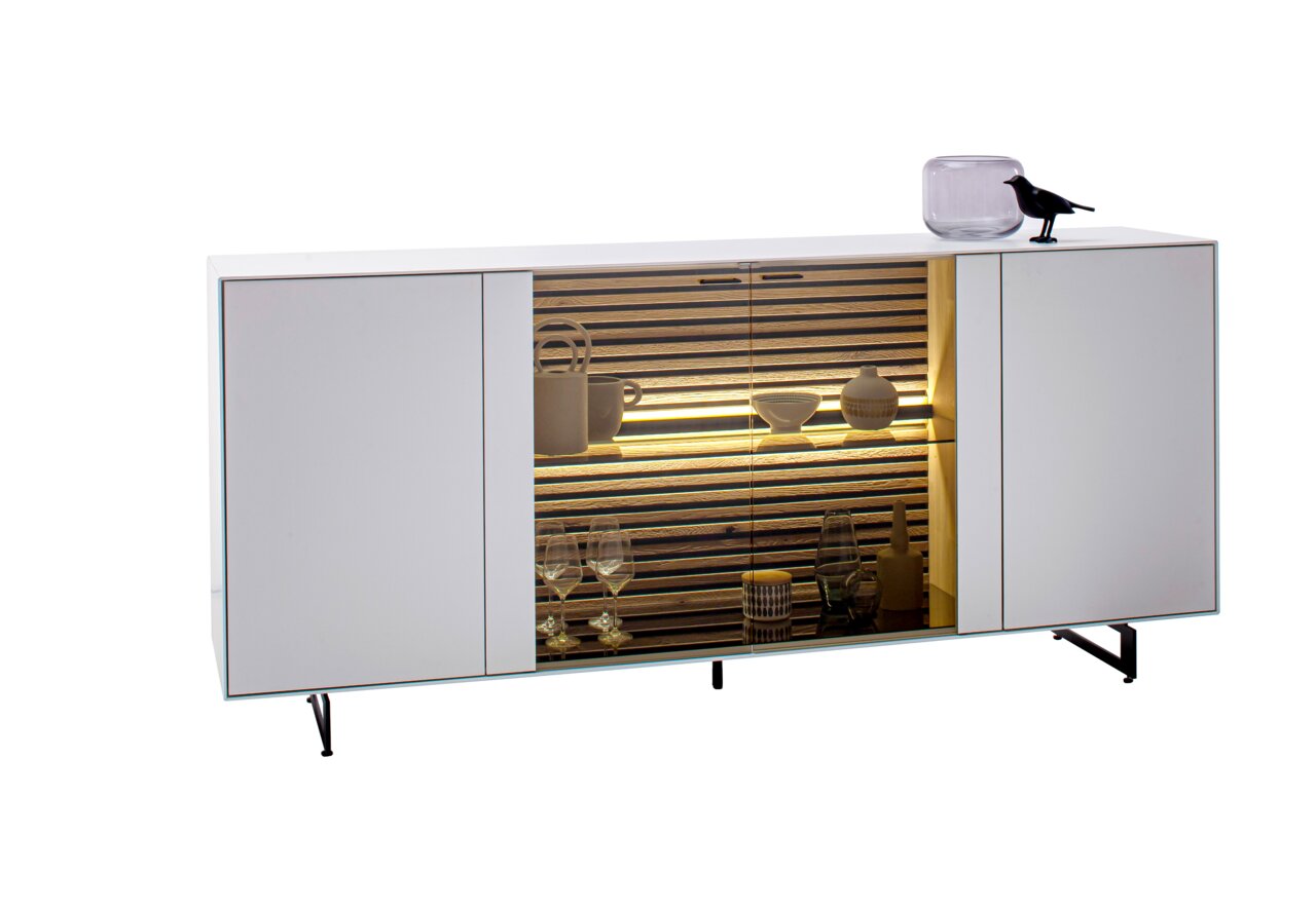 Schöner Wohnen Dressoir YONNA Modernes Sideboard mit weißem Finish, zentralem Glaseinsatz und dekorativer Beleuchtung, seitliche Perspektive.