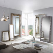 Mehrere große Spiegel mit dekorativen Rahmen in einem modernen Wohnzimmer, mit Blick auf eine helle Fensterfront.