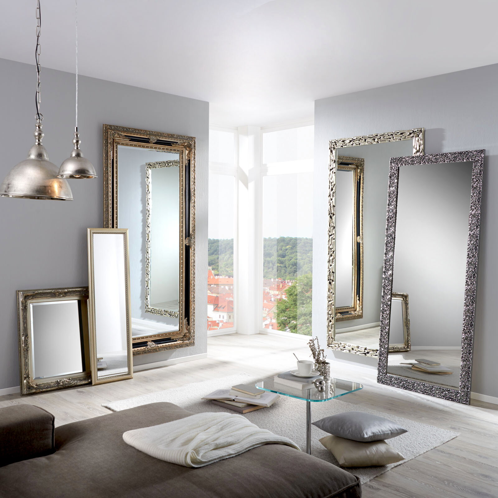 Mehrere große Spiegel mit dekorativen Rahmen in einem modernen Wohnzimmer, mit Blick auf eine helle Fensterfront.