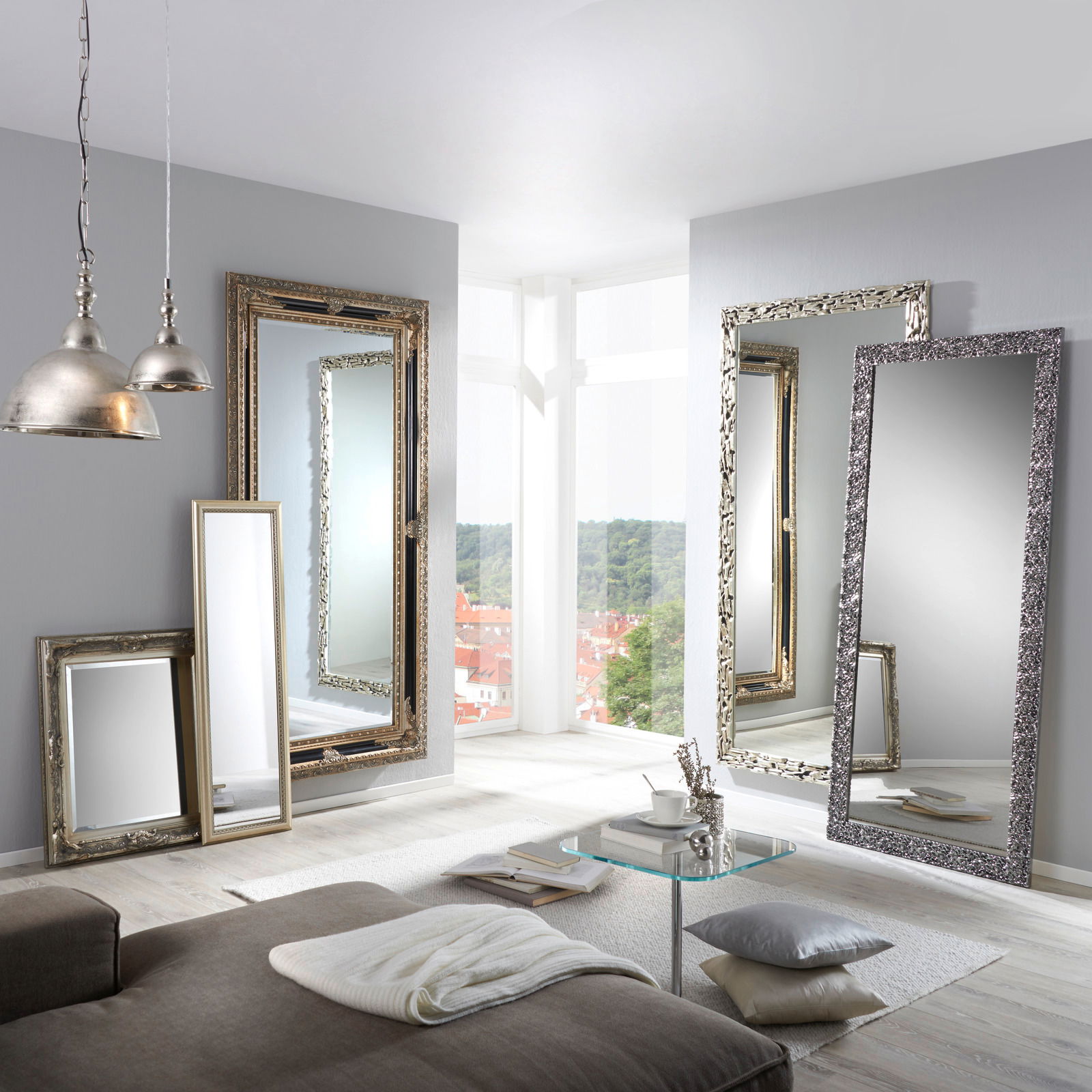 Mehrere große Spiegel mit dekorativen Rahmen in einem modernen Wohnzimmer, mit Blick auf eine helle Fensterfront.