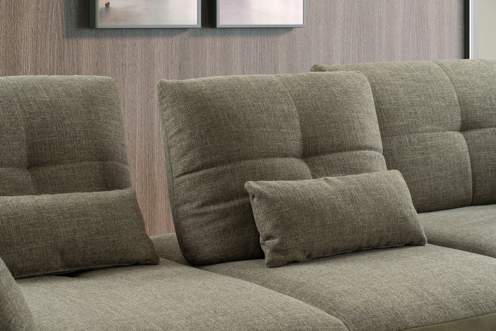 Nahaufnahme einer modernen, grauen Rundecke mit weichen, gepolsterten Kissen vor einer Holzwand.