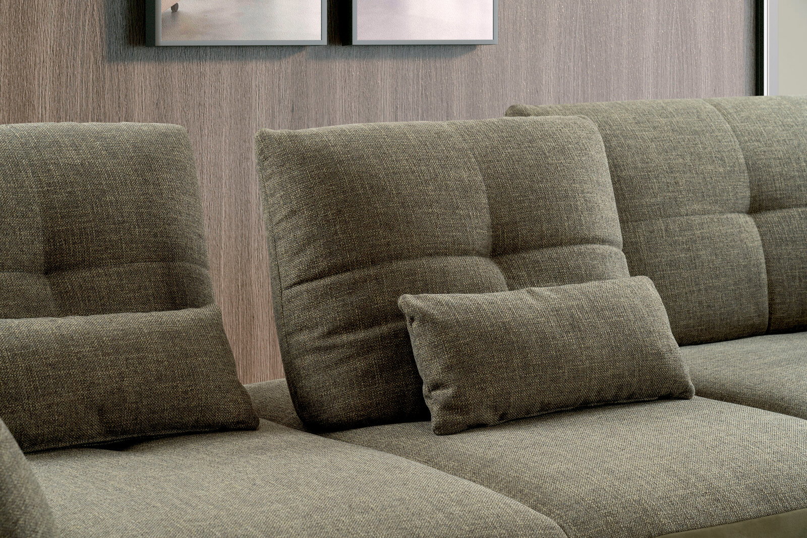 Nahaufnahme einer modernen, grauen Rundecke mit weichen, gepolsterten Kissen vor einer Holzwand.