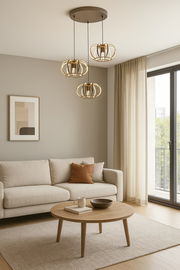 Moderne Pendelleuchte mit drei goldenen Lampenschirmen in einem stilvollen Wohnzimmer, seitliche Perspektive.