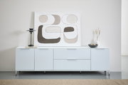 Frontale Ansicht eines modernen XL-TV-Lowboards in Weiß mit minimalistischer Dekoration, darunter eine abstrakte Kunstleinwand, eine schwarze Lampe und eine Vase.