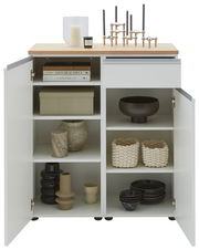 Frontale Ansicht einer weißen Kombi-Kommode mit offenen Türen, dekoriert mit Kerzen, Büchern und Vasen.