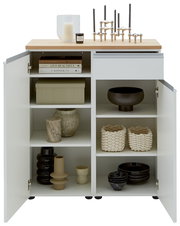 Frontale Ansicht einer weißen Kombi-Kommode mit offenen Türen, dekoriert mit Kerzen, Büchern und Vasen.