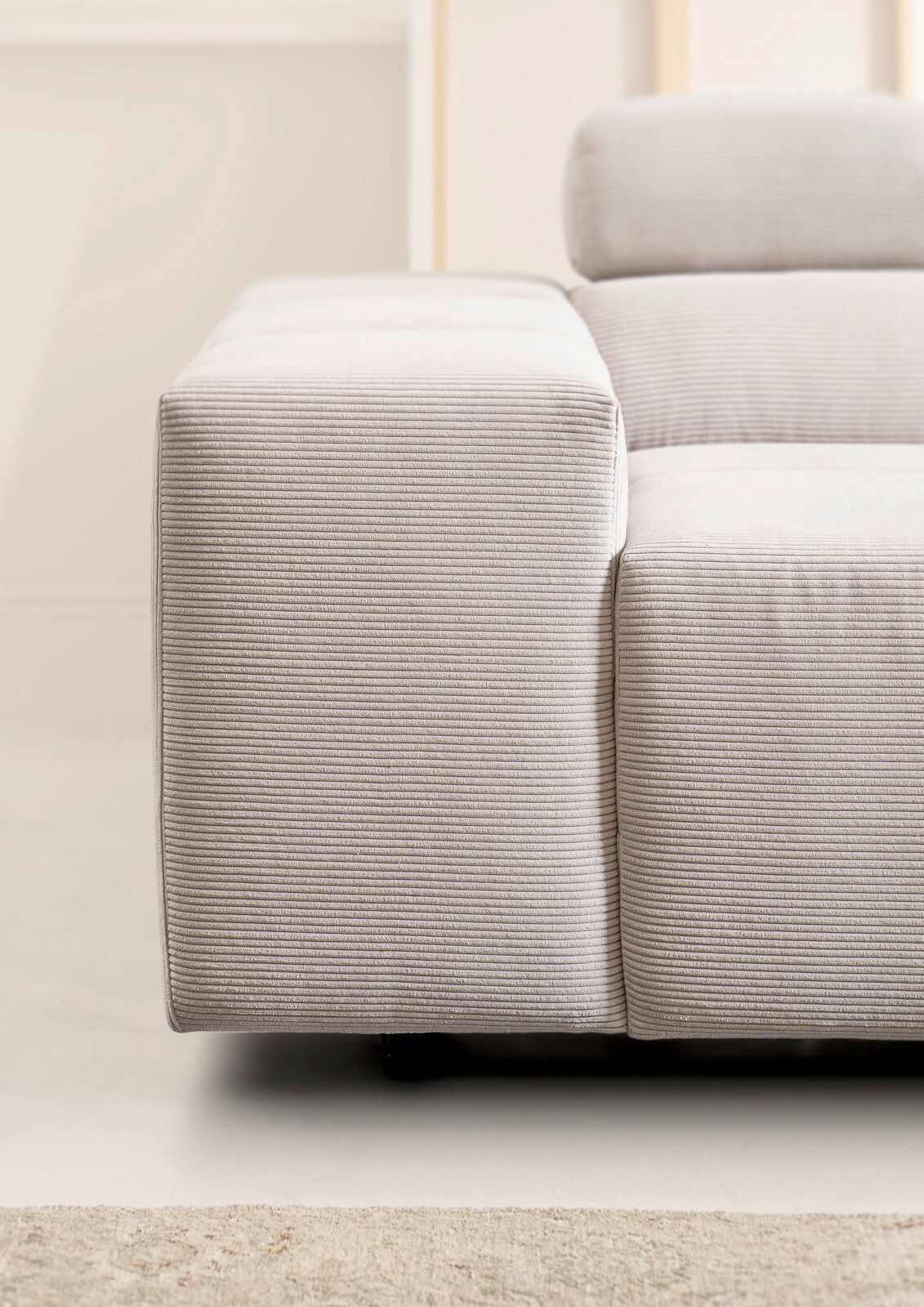 Nahaufnahme einer modernen, hellgrauen Rundecke mit feiner Streifenstruktur, seitliche Perspektive