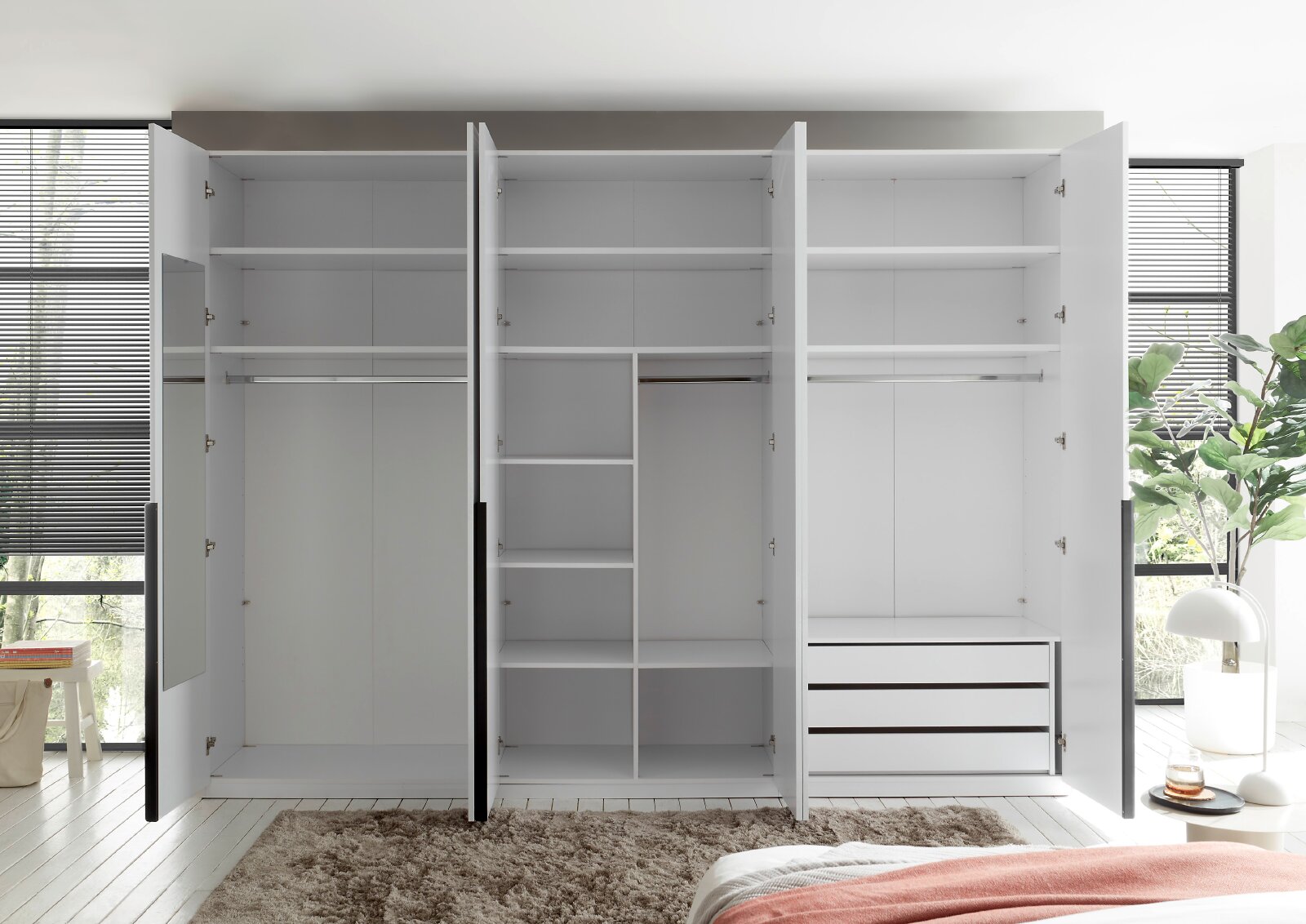 Großer moderner Kleiderschrank in Weiß und Anthrazit mit geöffneten Türen, Kleiderstangen, Regalfächern, drei Schubladen und integriertem Spiegel, frontal in einem hellen Schlafzimmer gezeigt