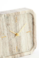 Nahaufnahme einer eleganten, quadratischen Uhr aus Marmor mit goldenen Zeigern und Markierungen.