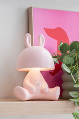 Niedliche LED-Tischlampe in Form eines sitzenden rosa Hasen mit leuchtendem Kopf, seitliche Perspektive