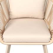 Nahaufnahme eines beigen Loungesessels mit geflochtenen Seiten und weichen Kissen, Vorderansicht.