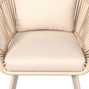 Nahaufnahme eines beigen Loungesessels mit geflochtenen Seiten und weichen Kissen, Vorderansicht.