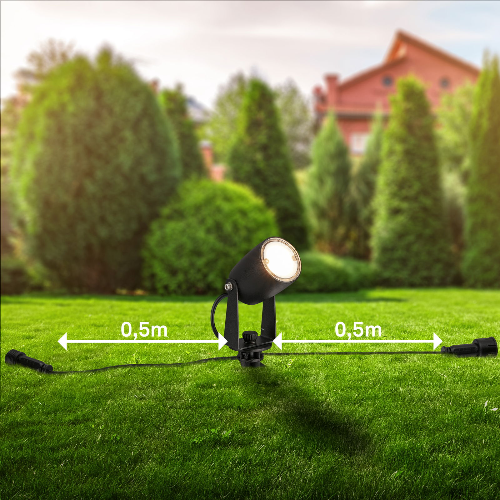 Erdspieß mit LED-Strahler in einem Garten, seitliche Perspektive, mit 0,5 m Abstand zwischen den Anschlüssen.