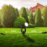 Erdspieß mit LED-Strahler in einem Garten, seitliche Perspektive, mit 0,5 m Abstand zwischen den Anschlüssen.