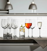Verschiedene Kelchgläser und ein Longdrinkglas auf einem Tisch, seitliche Perspektive.